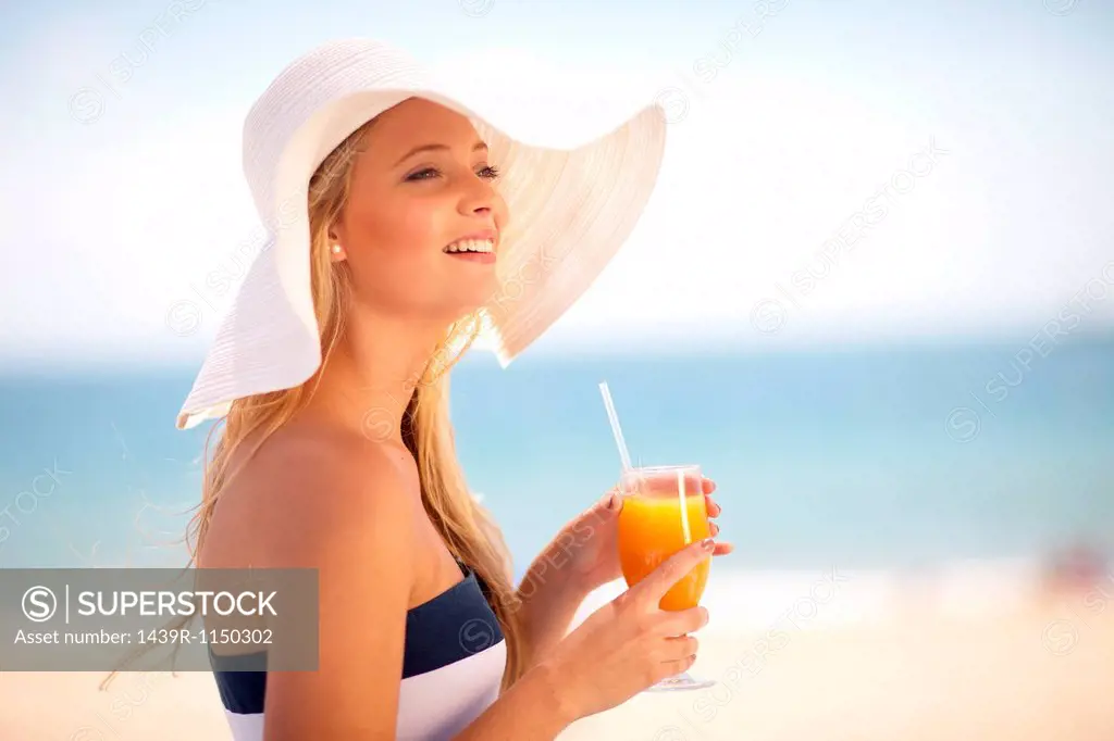 Woman in floppy hat having juice