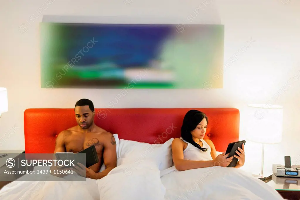 Couple using e_readers in bed