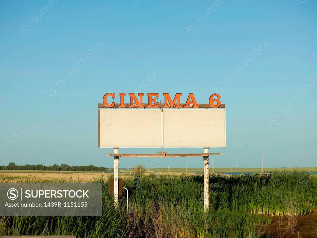 Abandoned drive-in movie sign in field