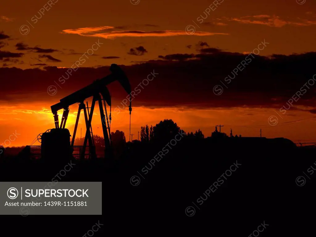 Silhouette of oil well at sunset