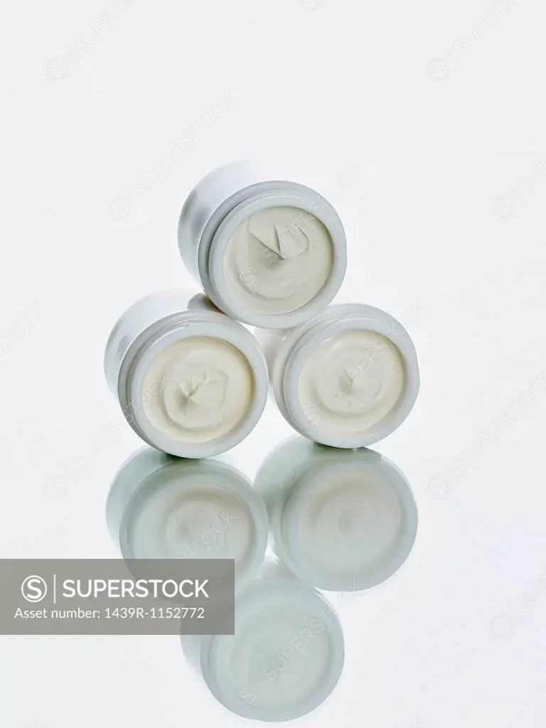 Pots of lotion stacked on counter