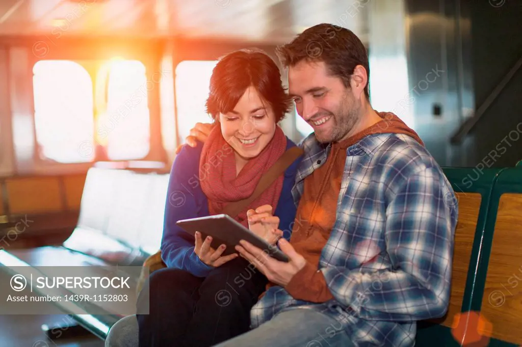 Couple using tablet computer on ferry