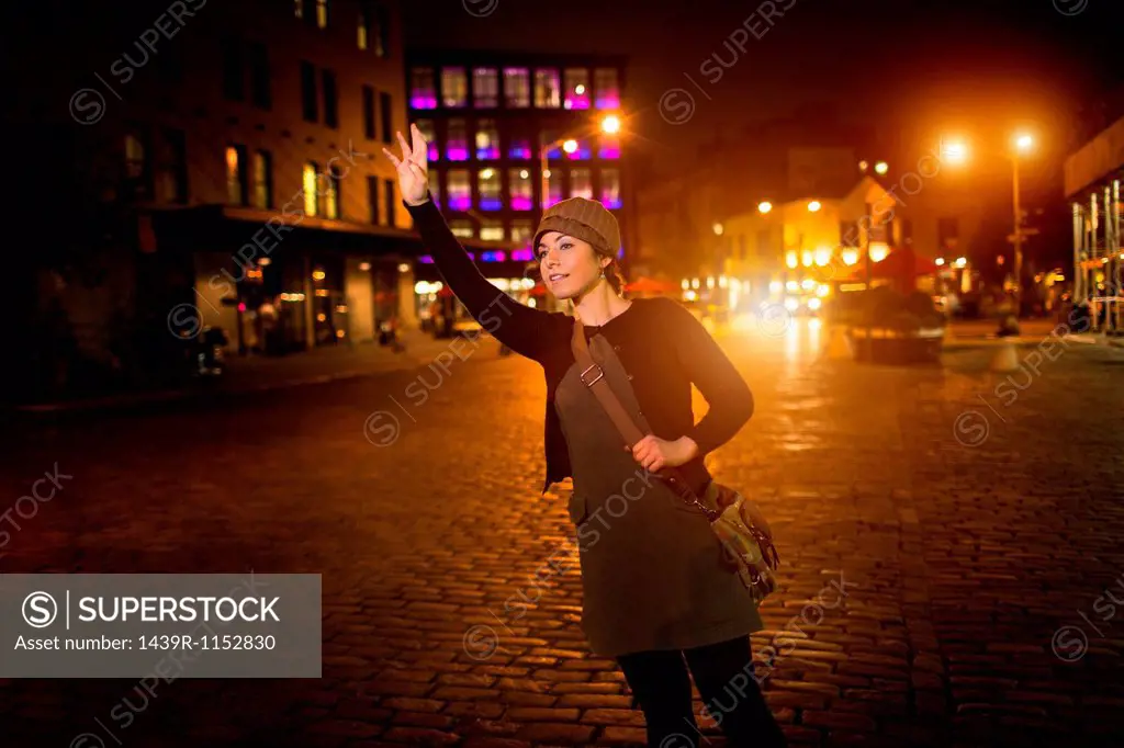 Woman hailing taxi on city street