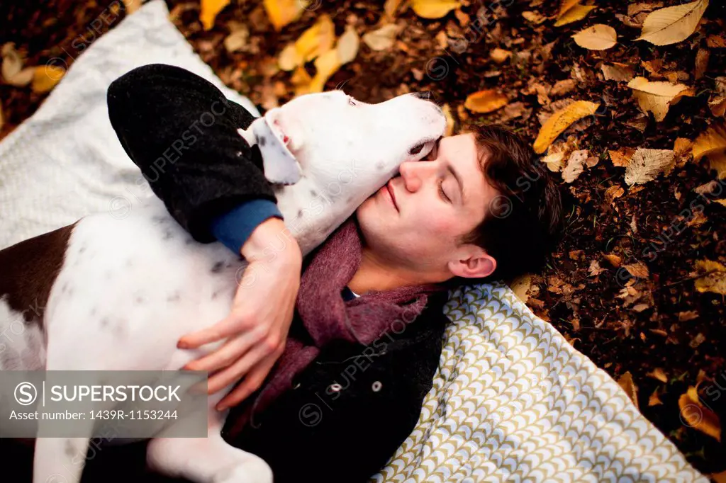 Man and dog hugging on picnic blanket