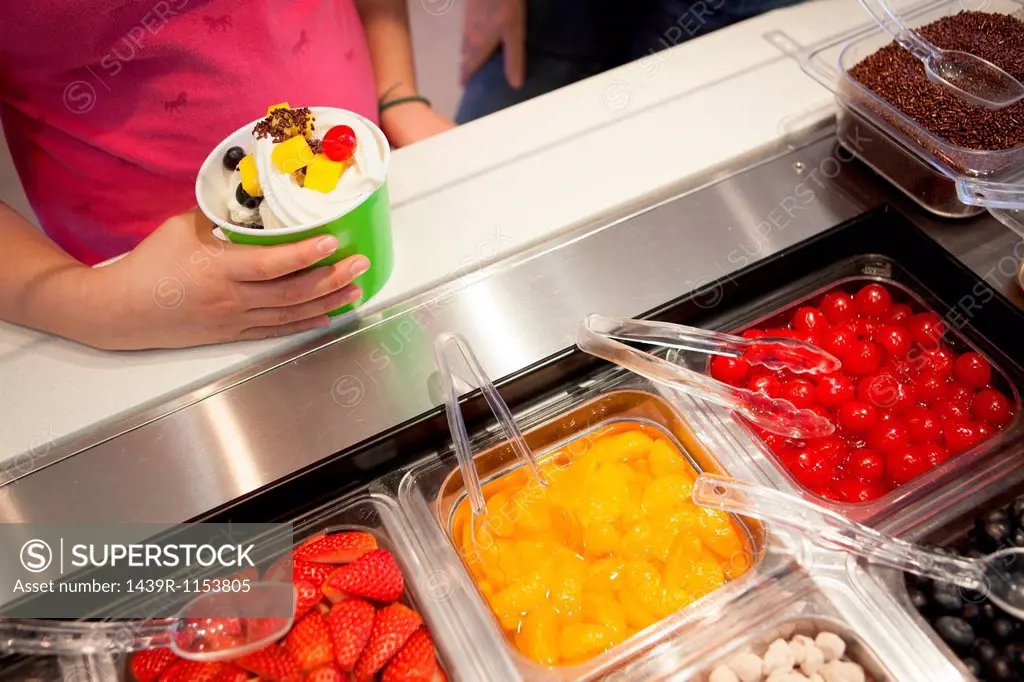 Girl putting toppings on frozen yogurt