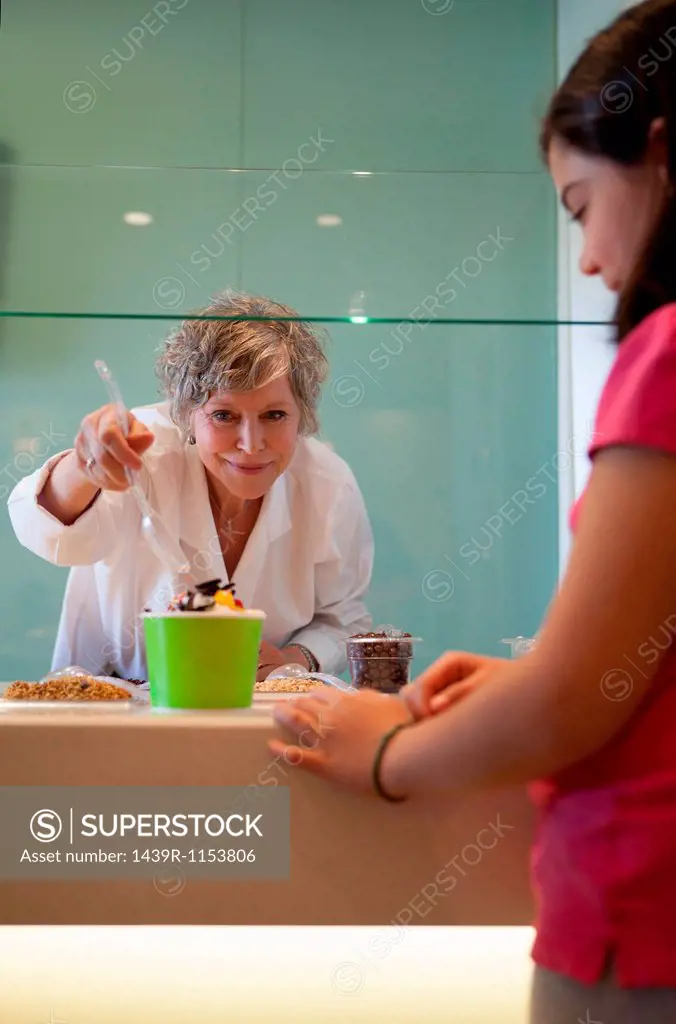 Cashier putting toppings on yogurt