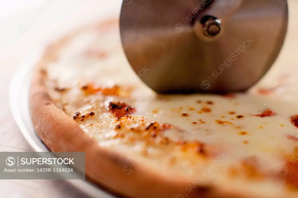 Close up of cutter slicing pizza