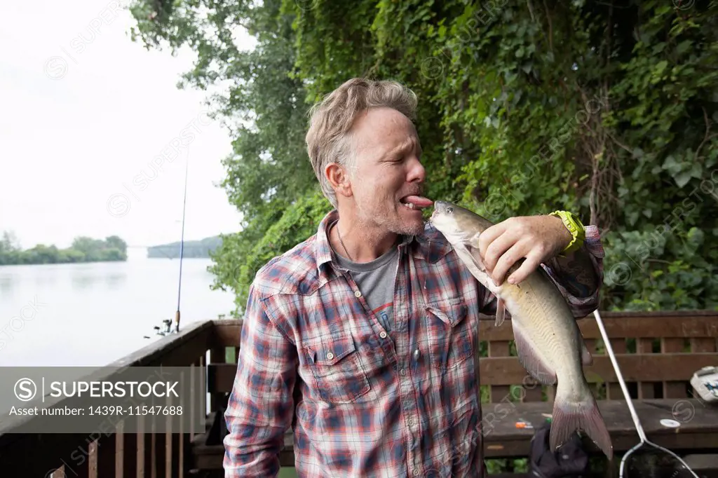 Man sticking out tongue at catfish, river Raisin, Monroe, Michigan, USA
