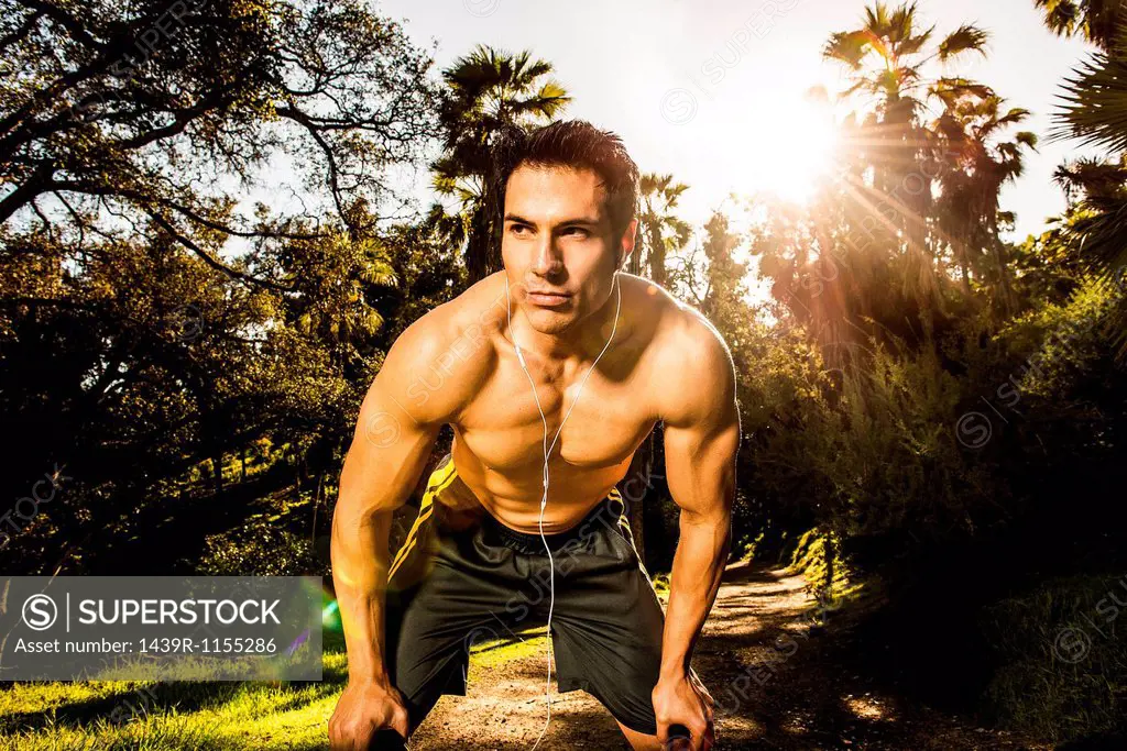 Young man exercising in forest resting