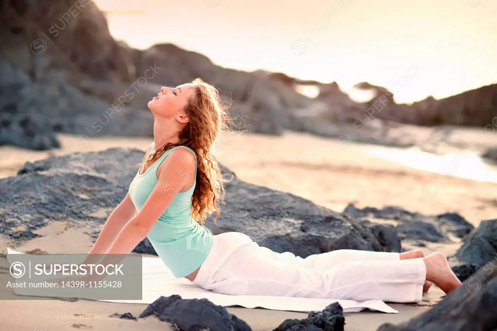Young woman doing yoga on beach