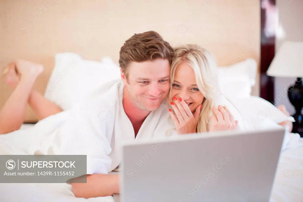 Young couple on bed using laptop