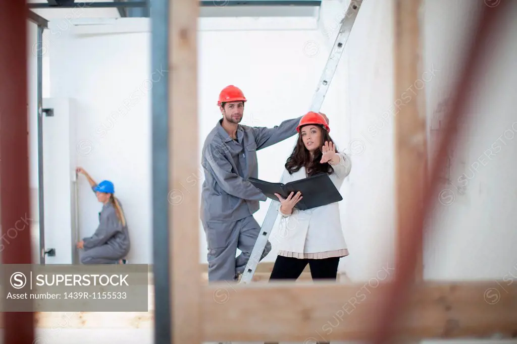 Female architect discusses plans with laborer on construction site