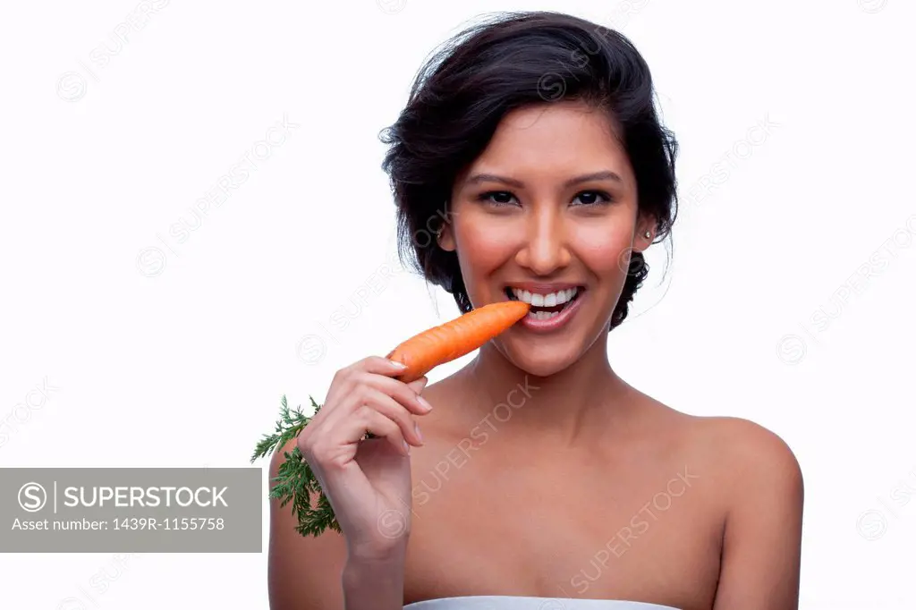 Young woman biting carrot
