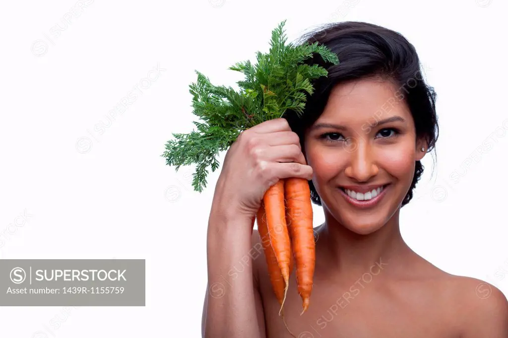 Young woman holding bunch of carrots