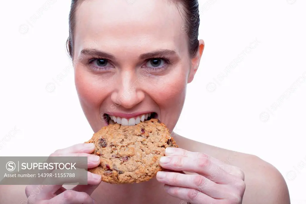 Young woman biting cookie