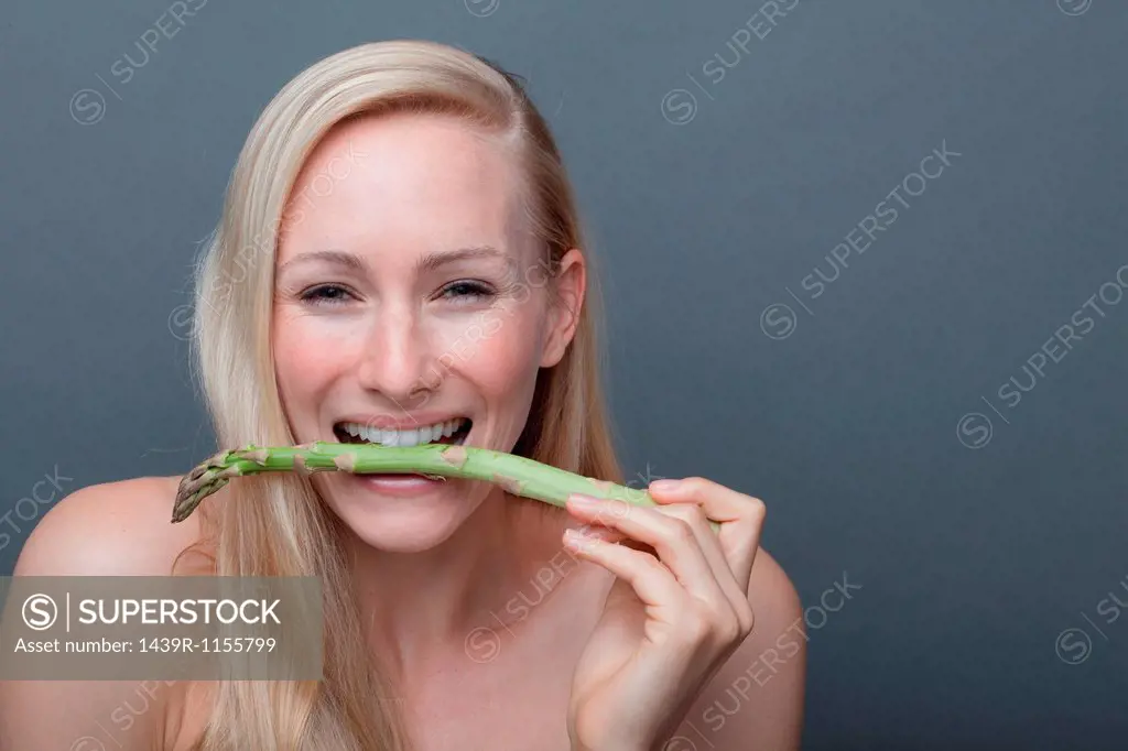 Young woman biting asparagus