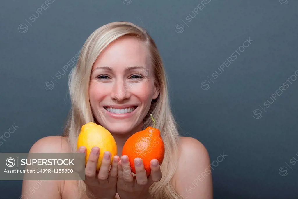 Young woman holding orange and lemon