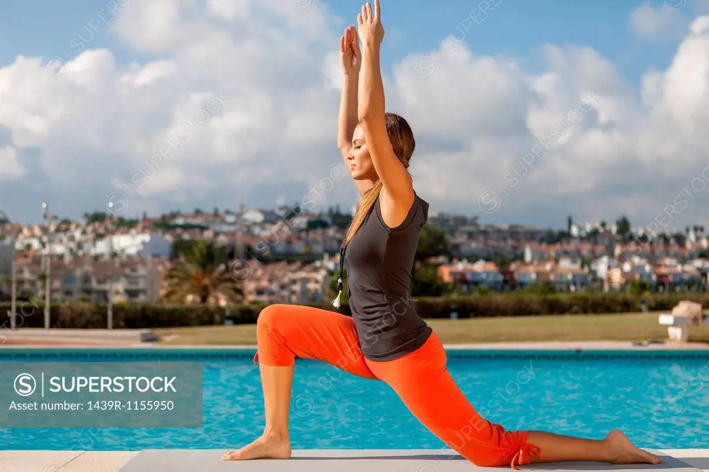 Young woman doing yoga at poolside