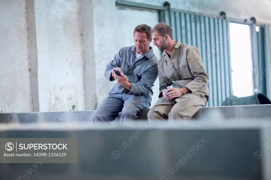 Man showing something on smartphone to work colleague