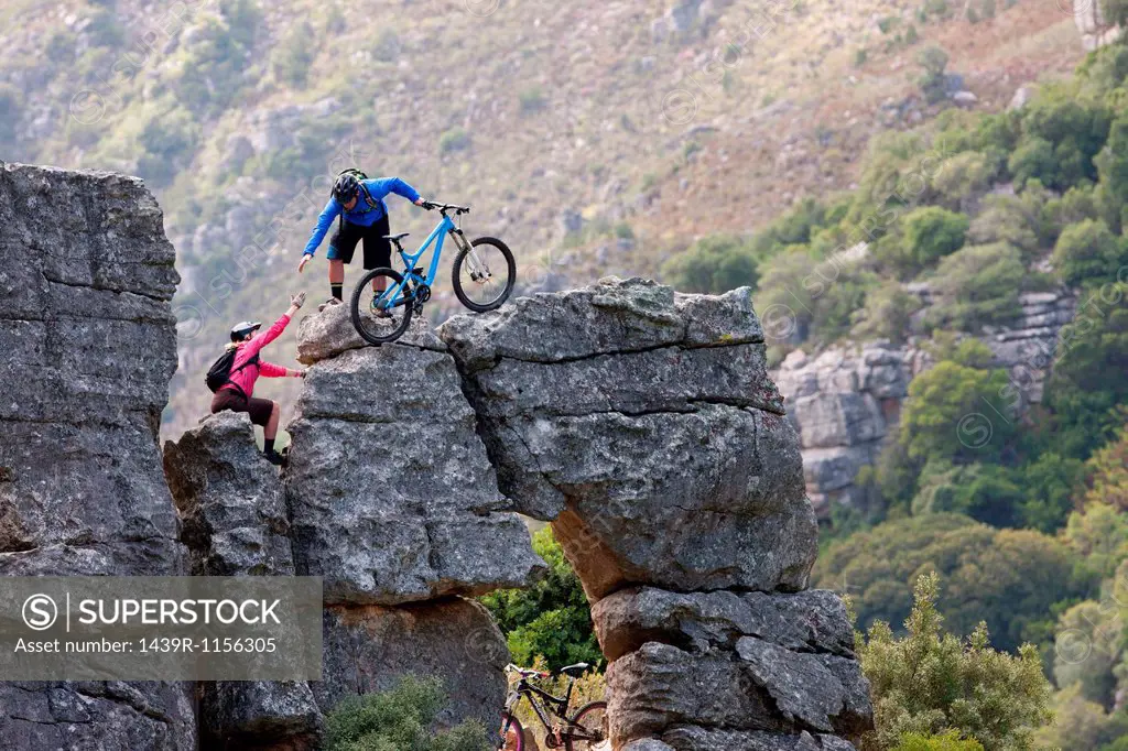 Mountain biking couple climbing rock formation