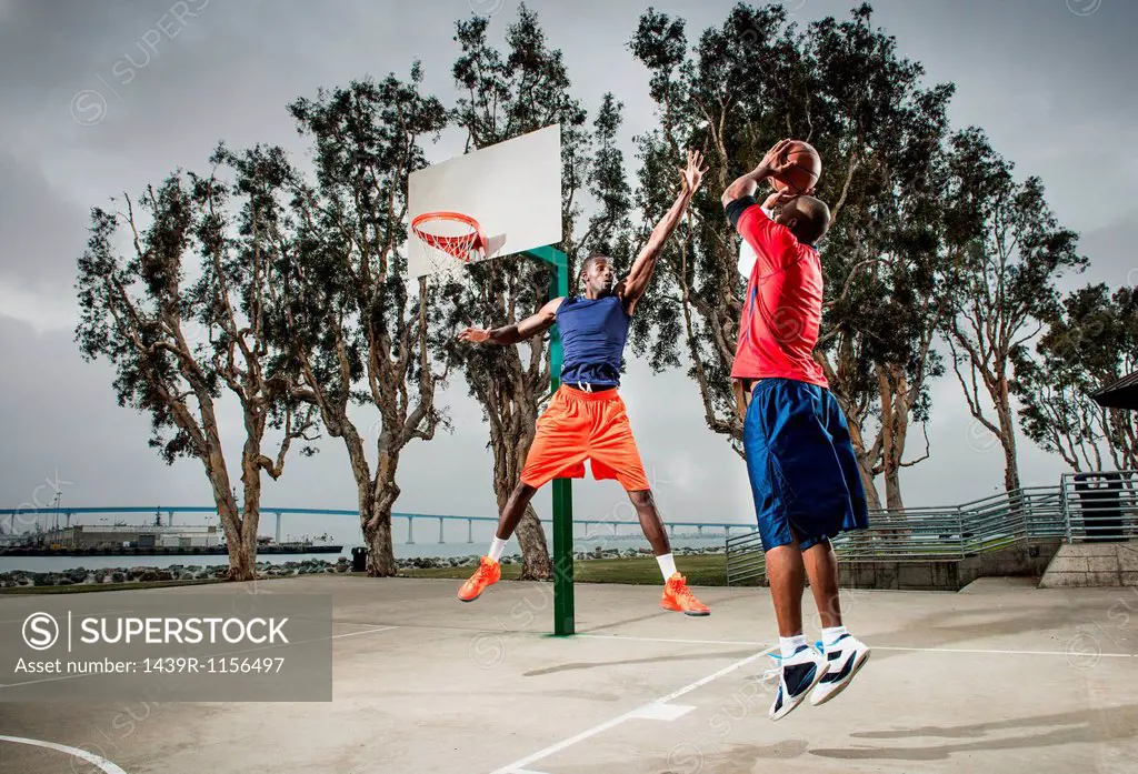 Young basketball players jumping to score hoop