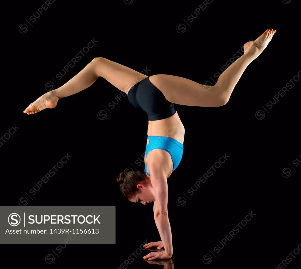 Acrobat performing handstand in front of black background