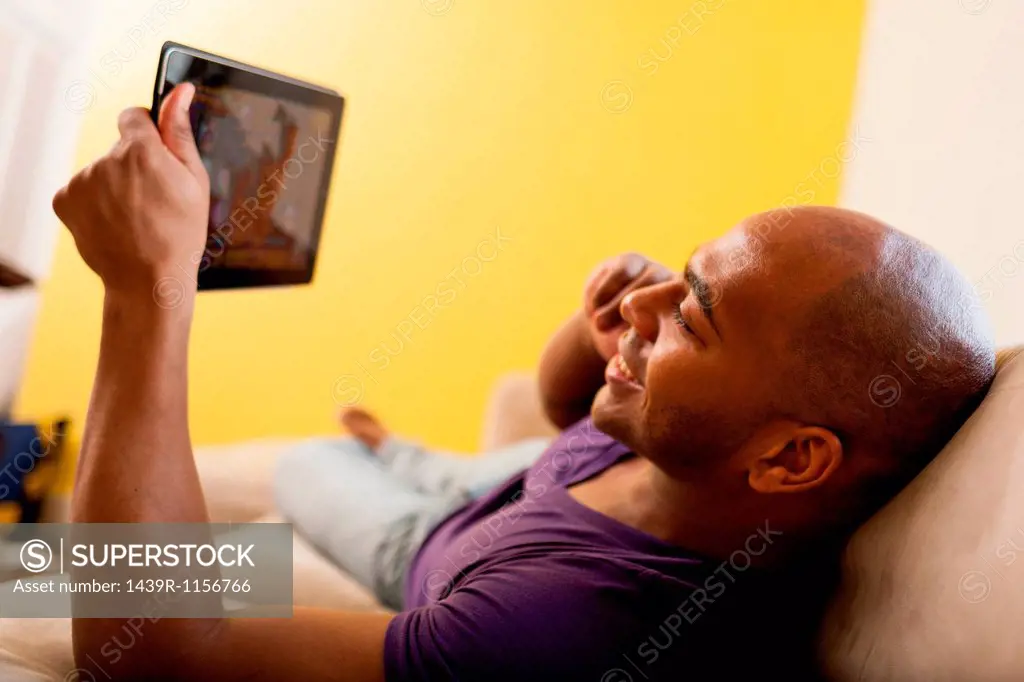 Mid adult male on sofa holding digital tablet and mobile phone