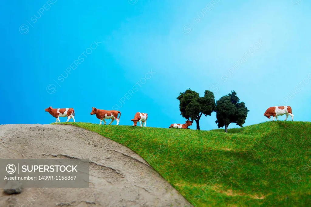 Model cows on pretend grass with trees