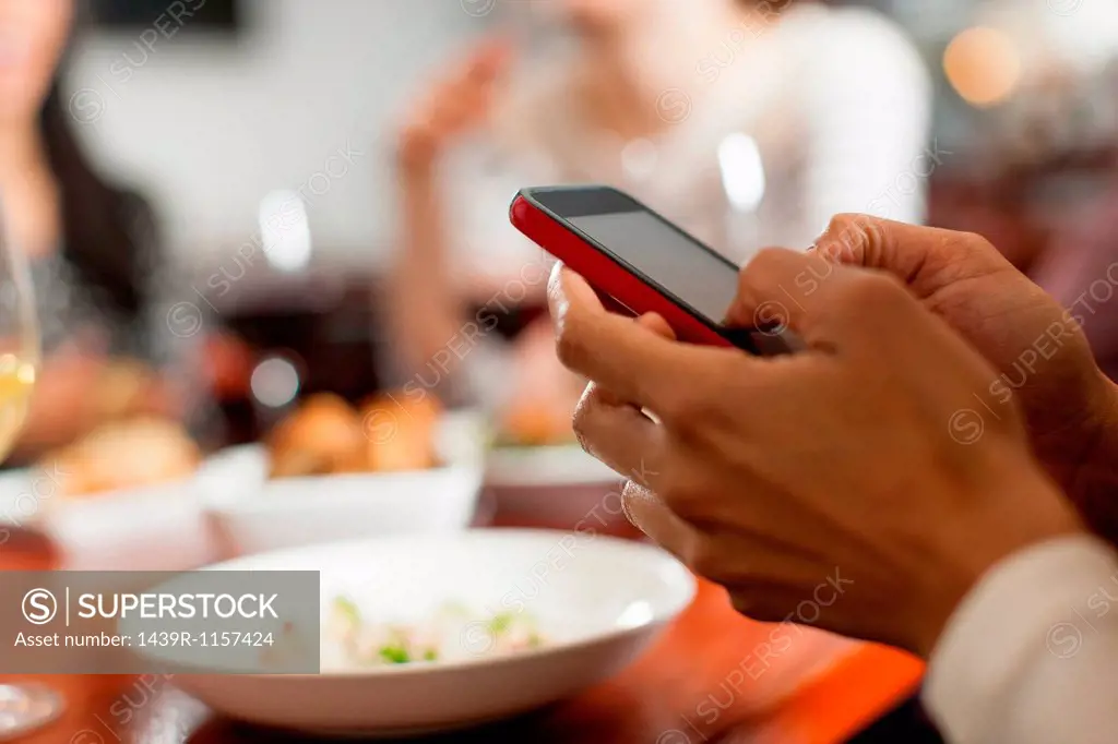 Woman texting during meal with friends