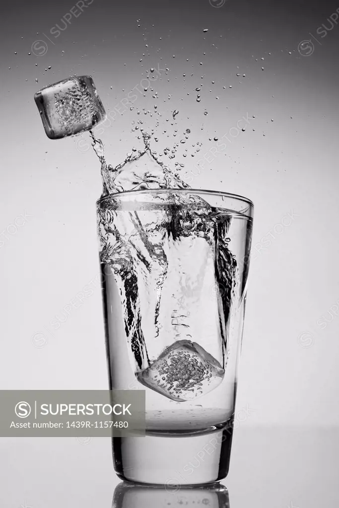 Ice cubes falling into glass of water