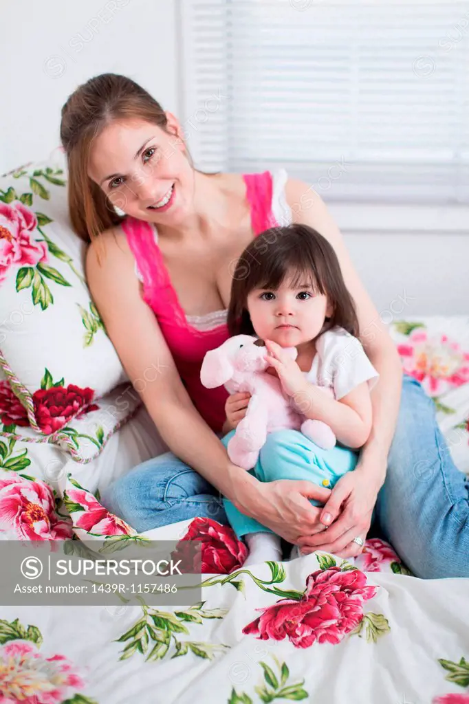 Mother and toddler sitting on bed