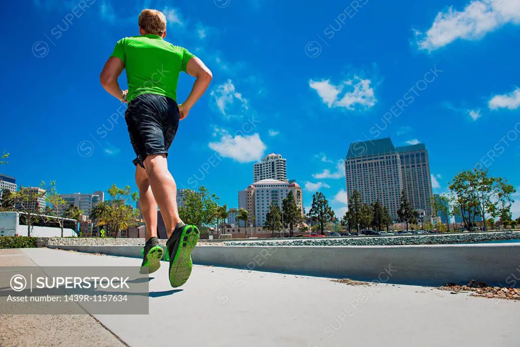 Young man jogging in city, rear view