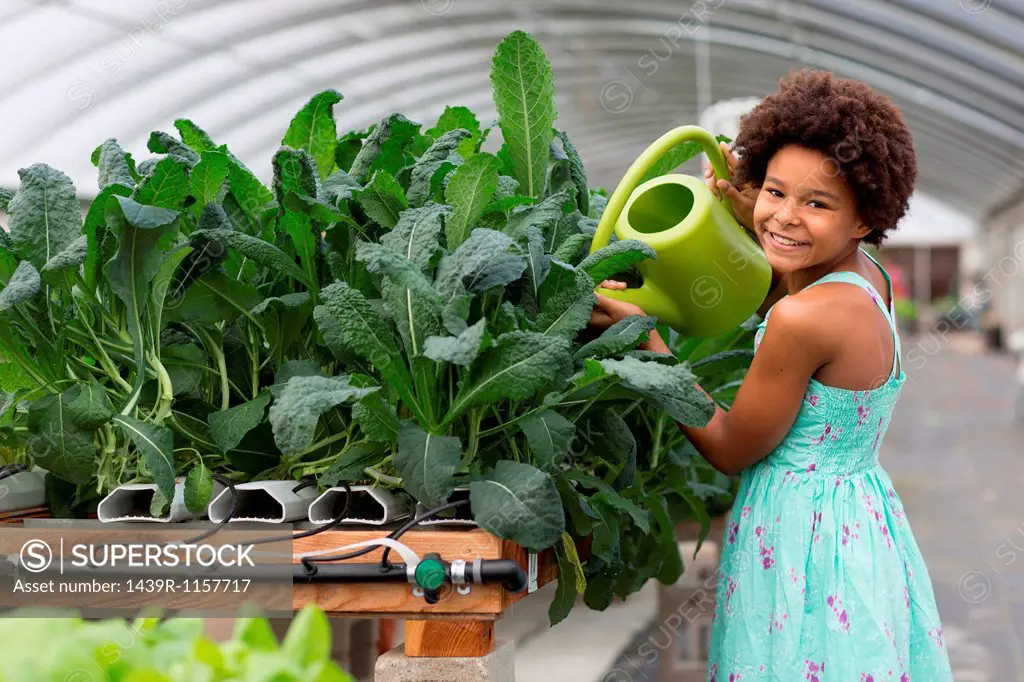 Girl watering plants in greenhouse