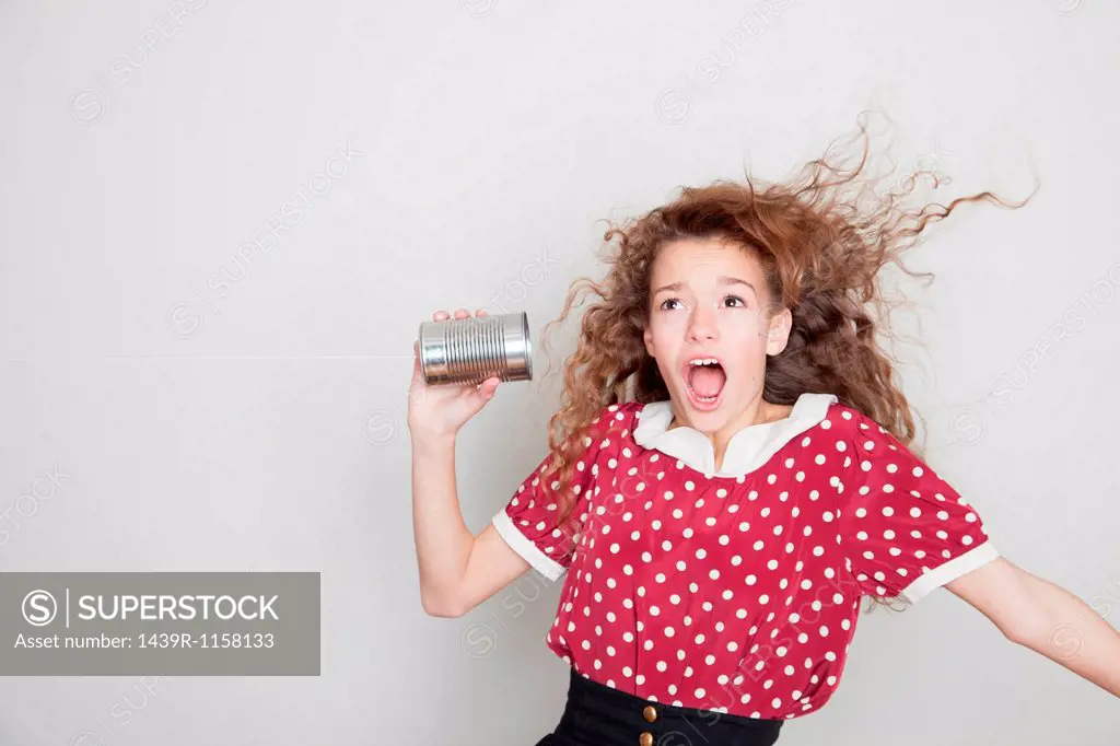 Girl with tin can telephone, mouth open