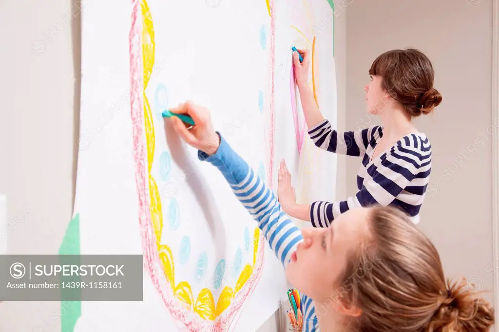 Girls drawing mural on wall