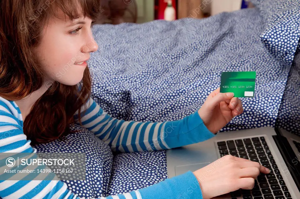 Girl lying on bed with laptop internet shopping