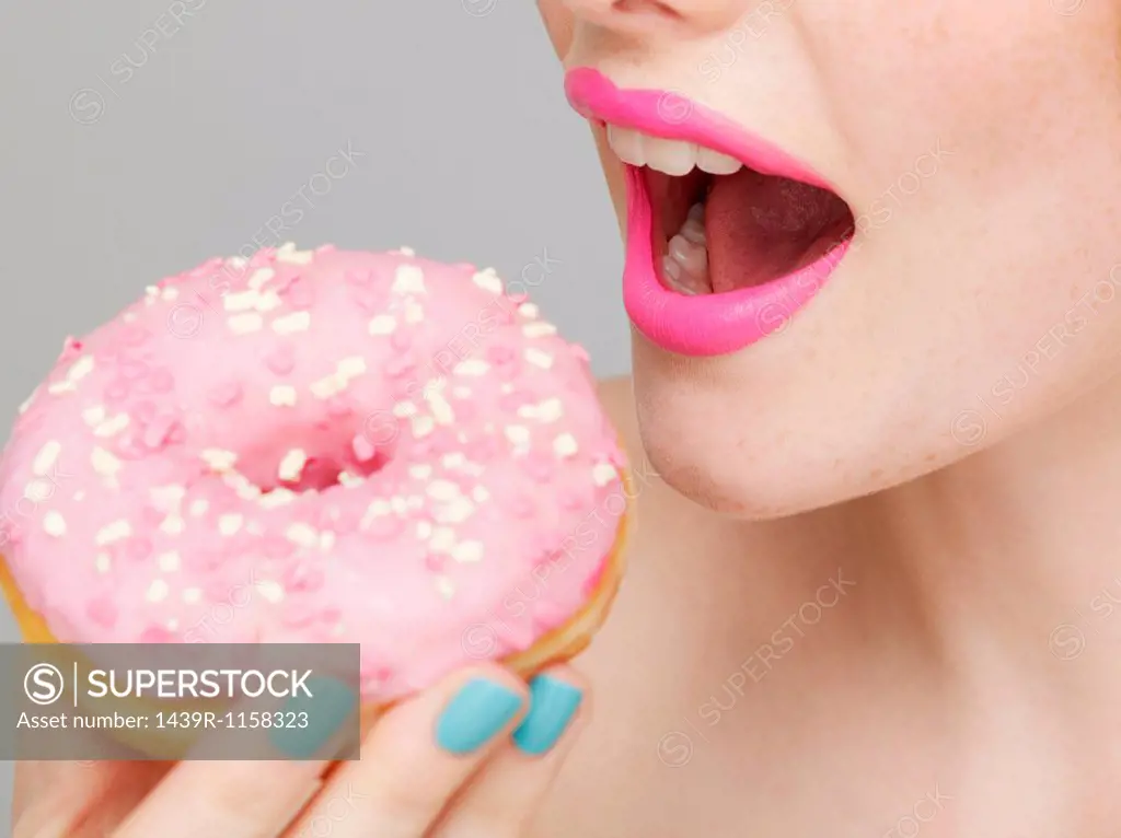 Woman wearing pink lipstick eating doughnut