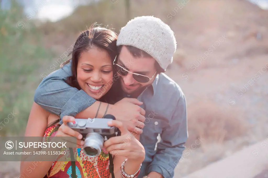 Couple embracing and holding camera on road trip, smiling