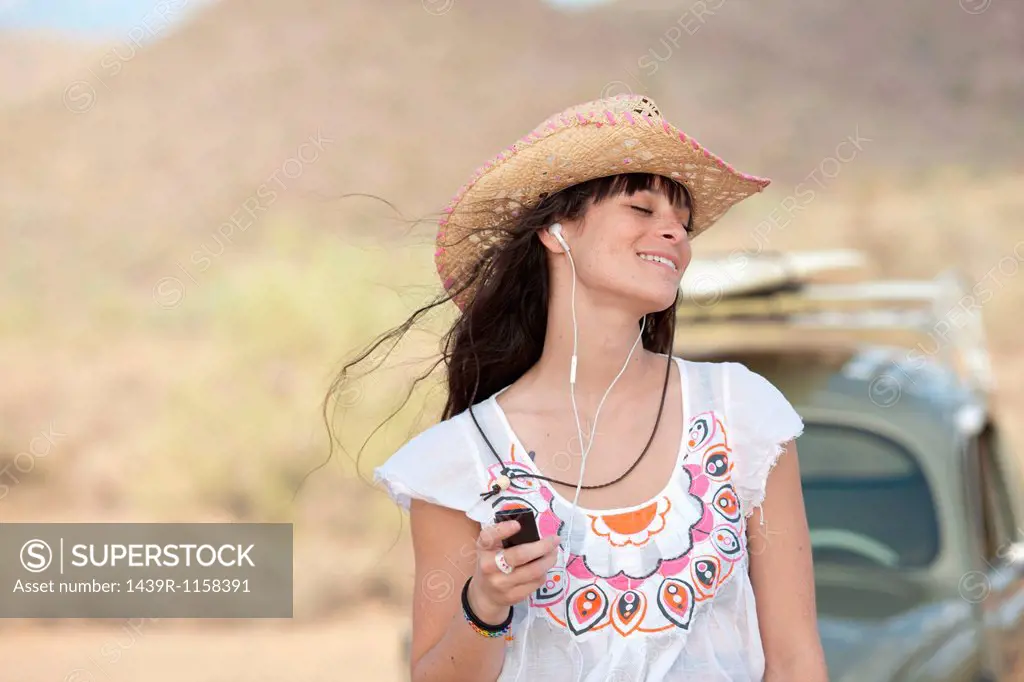 Young woman in cowboy hat wearing earphones, smiling