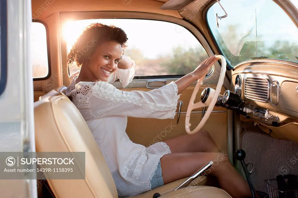 Young woman sitting in car on road trip, portrait