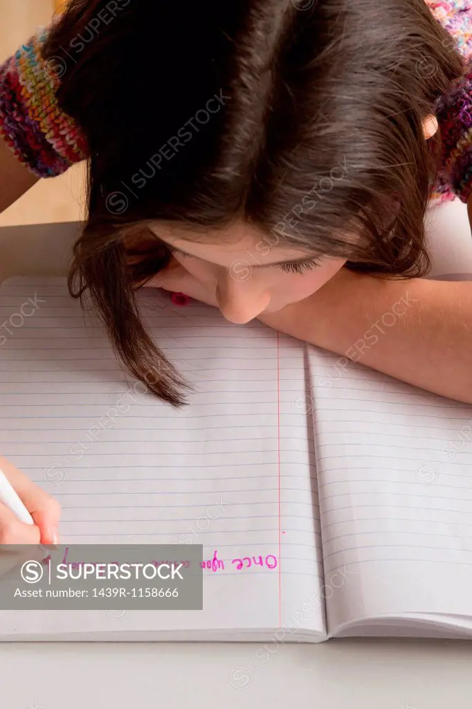 Girl writing in pink felt tip pen in notebook