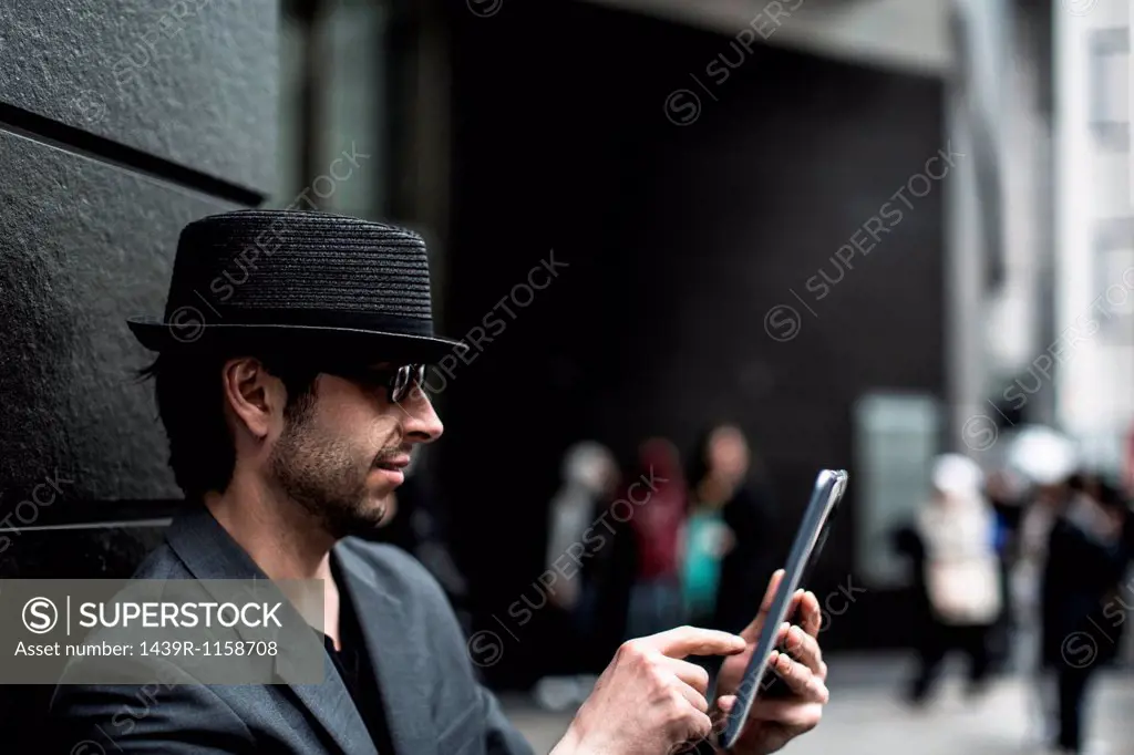 Portrait of man using digital tablet on city street