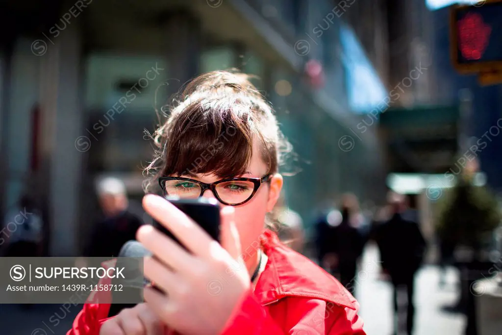 Woman on city street looking at smartphone