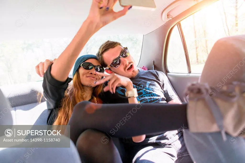 Couple on backseat in car photographing themselves