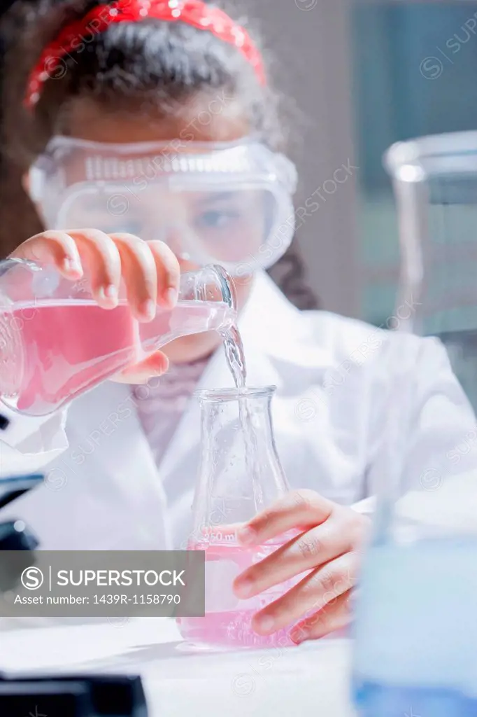 Girl pouring chemicals into conical flask
