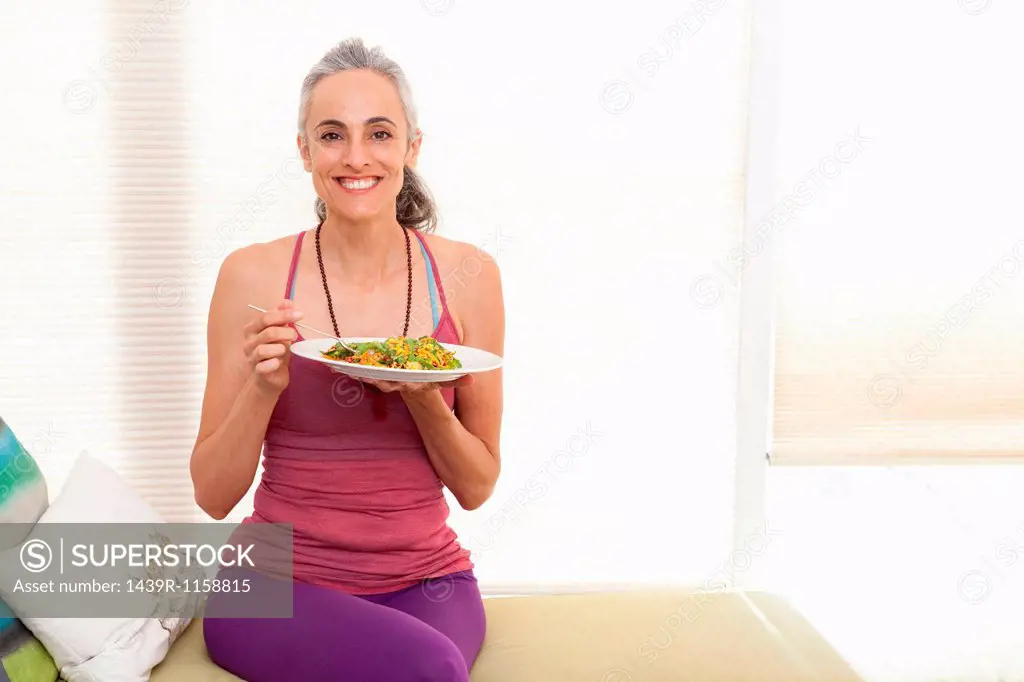 Woman sitting on window seat eating lunch, portrait