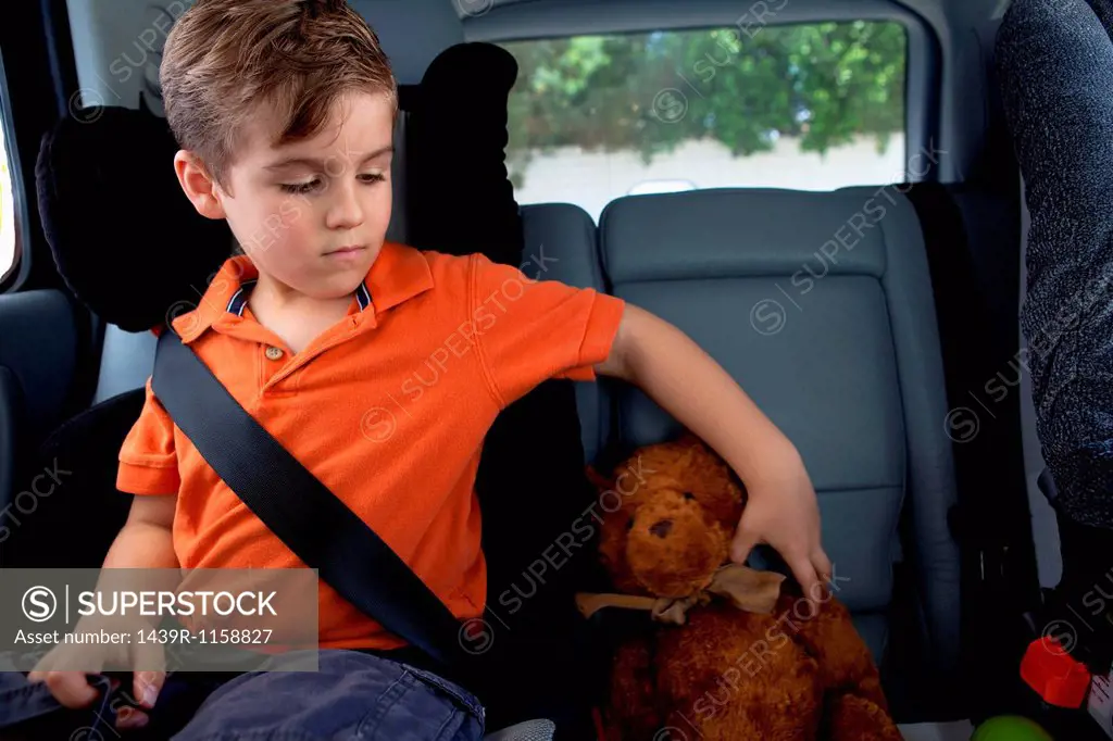 Boy in child safety seat in car with teddy bear