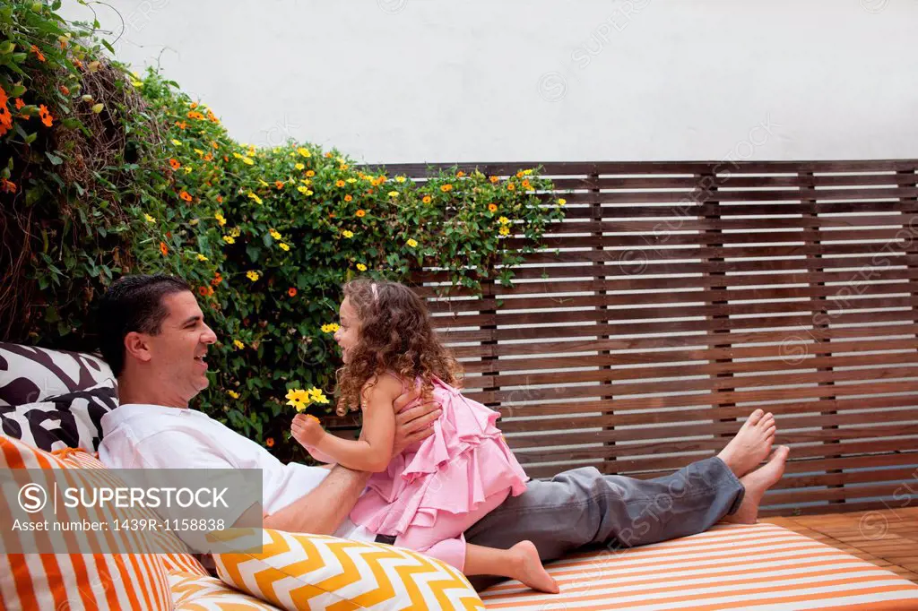 Father and daughter relaxing outdoors, girl holding flowers