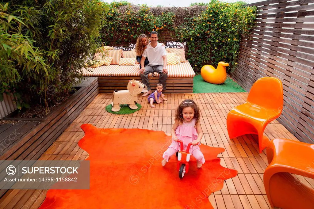 Parents relaxing outdoor with children playing on patio