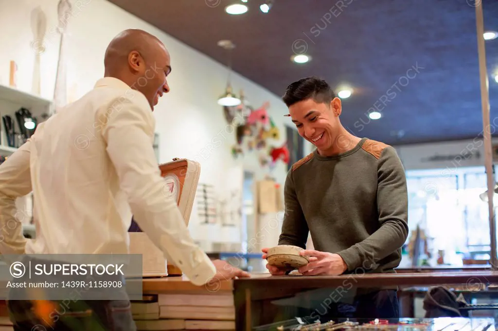 Young man buying item from shopkeeper in vintage shop